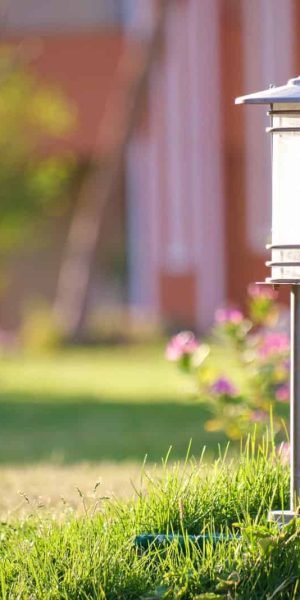 Outdoor landscape lighting with modern lamp post and garden flowers.