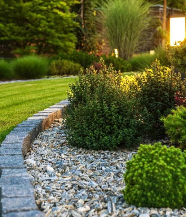 Beautiful landscaped garden with stone edging, lush greenery, and decorative plants.